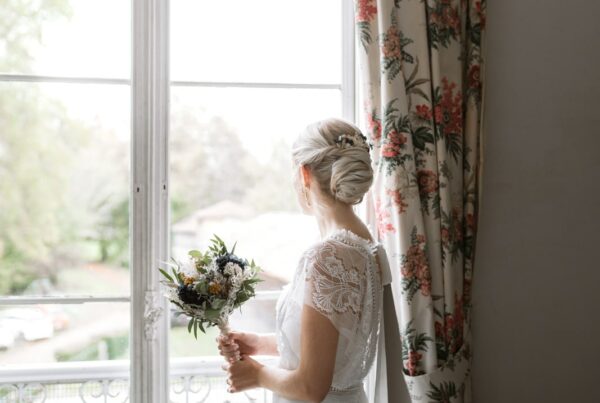 Préparatifs de la mariée qui regarde arriver son futur mari, bouquet à la main